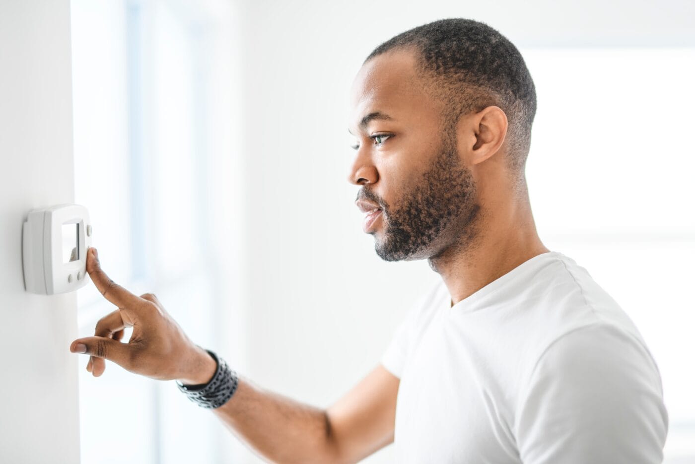 A man changing the temperature on his home's programmable thermostat.